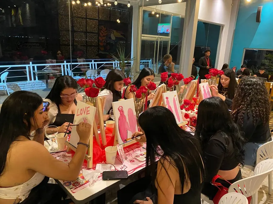Grupo de amigas pintando lienzos en una mesa decorada con rosas
