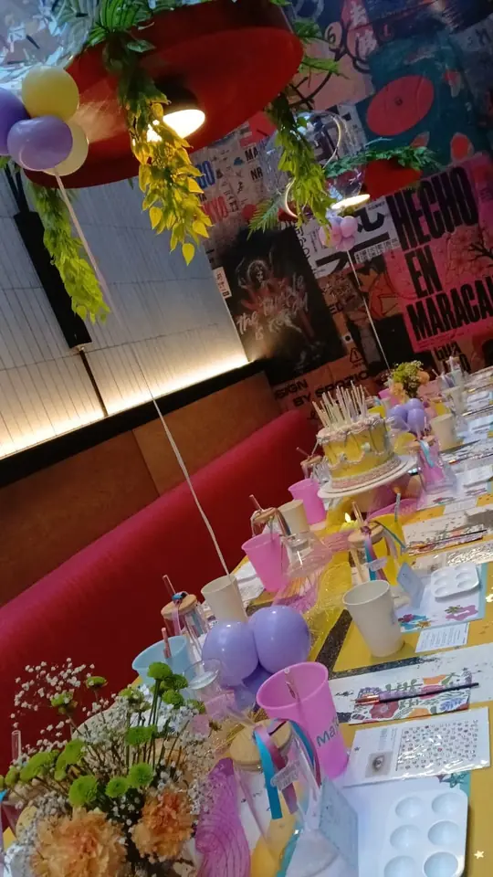 Mesa de fiesta con globos, flores y materiales de pintura