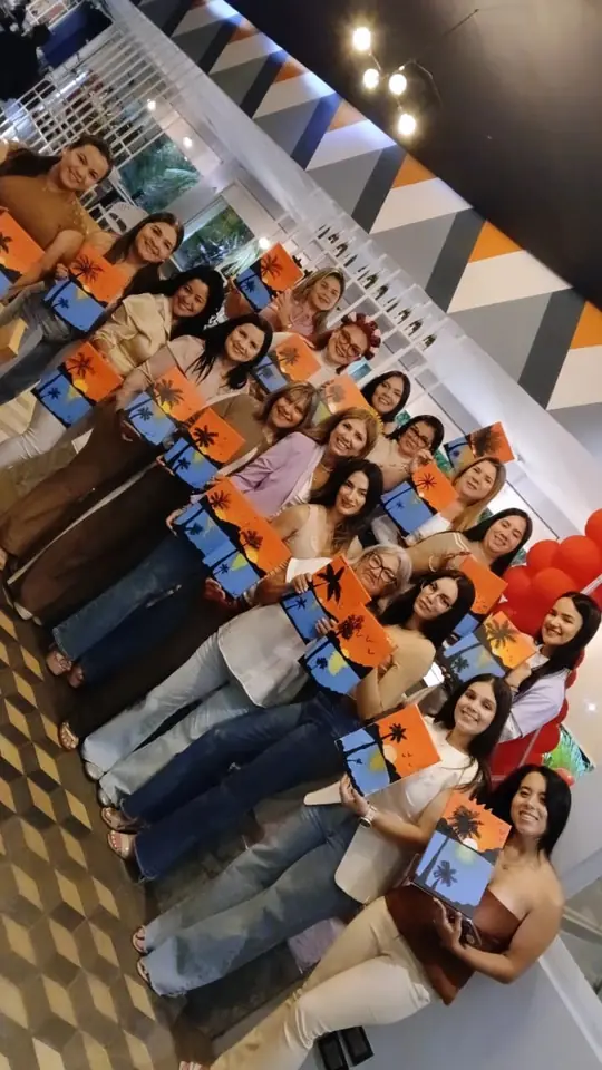 Grupo de invitadas mostrando sus pinturas de atardeceres con palmeras