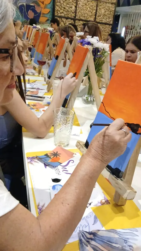 Invitada pintando un atardecer en un lienzo pequeño