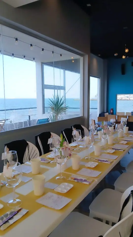 Mesa larga preparada para un taller frente a una ventana con vista al mar