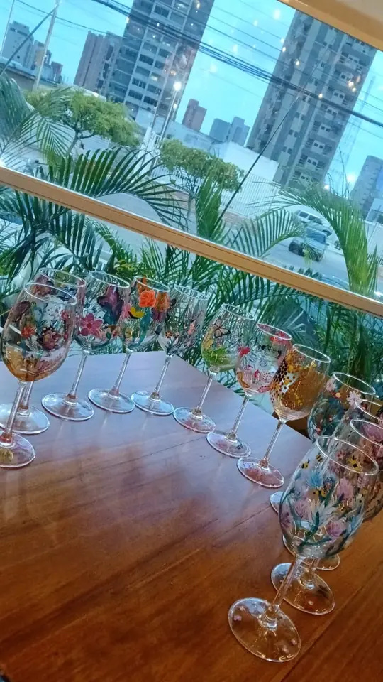 Copas de vidrio pintadas a mano con flores, alineadas sobre una mesa